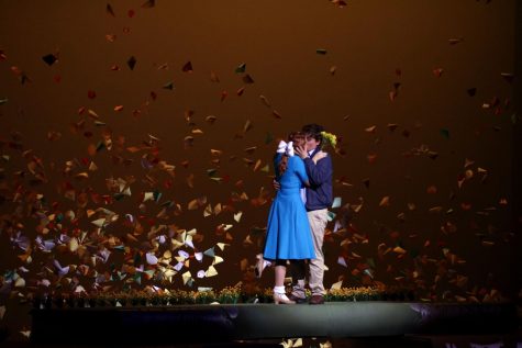 Musical leads Janson Hanes and Alexandra Walls act out an intimate moment between their characters as daffodils cascade behind them.