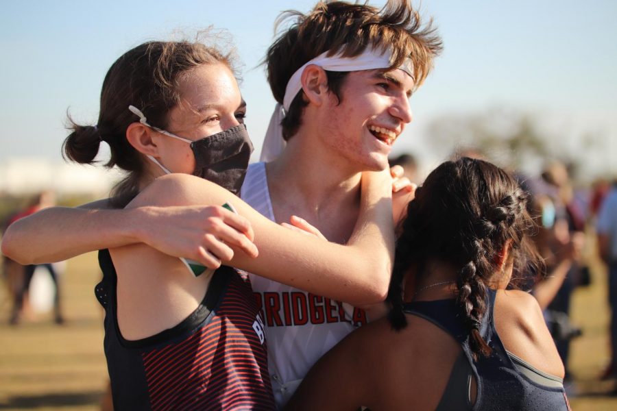 In celebration of the varsity boys cross countrys third place finish at the Region cross Country meet, Jacob Grosch, Macie Gunn, and Allison Milan share a hug.