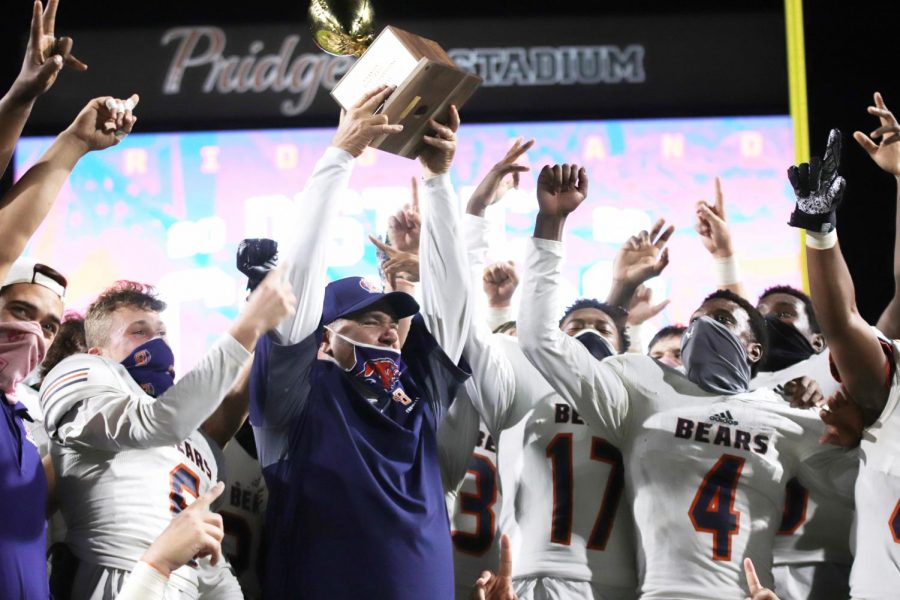 After earning the title of district champs, the Bridgeland varsity football team celebrates their victory with the trophy.