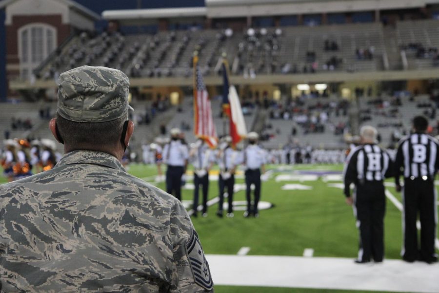 Captain Michael Claiborn stands on the sidelines as ROTC cadets present the flags during the National Anthem at the varsity football game against Cy Park. 